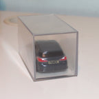 Small model car in a clear box on a desk with a plain background
